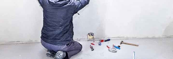 Person mit Zollstock an Wand